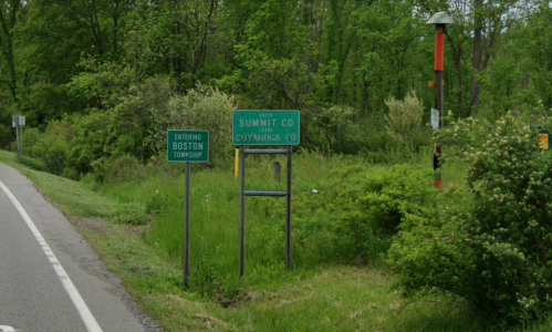 Roadside signs indicating the entrance to Boston Township and Summit County, surrounded by greenery.