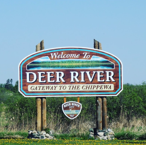 Welcome sign for Deer River, labeled "Gateway to the Chippewa," with a scenic background and decorative elements.