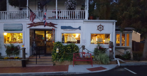 A charming coastal restaurant with nautical decor, warm lights, and a welcoming entrance surrounded by greenery.