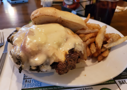 A plate featuring a cheesy burger with a toasted bun and a side of crispy French fries.