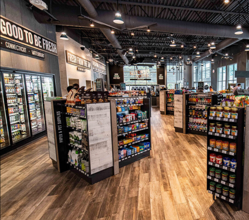 Interior of a modern grocery store with shelves of beverages and snacks, featuring a spacious layout and bright lighting.