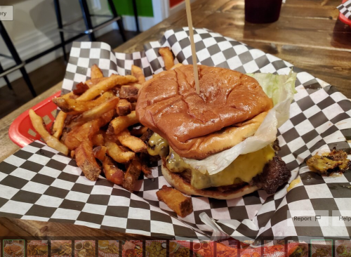 A cheeseburger with lettuce on a checkered plate, accompanied by a side of crispy fries.