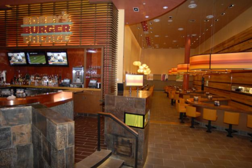 Interior of a modern burger restaurant with a bar, seating area, and warm lighting.