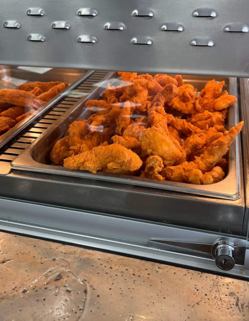 A tray of golden-brown fried chicken pieces in a display case.