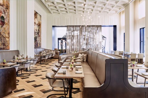 Elegant restaurant interior featuring modern decor, plush seating, and artistic lighting. Tables set for dining.