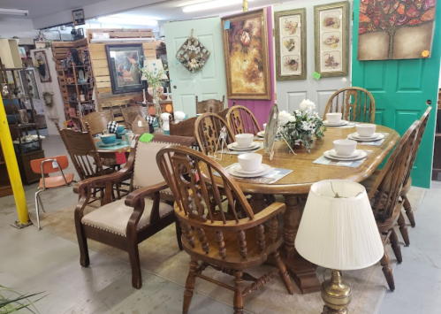 A cozy dining area featuring a wooden table set for six, surrounded by various chairs and decorative wall art.