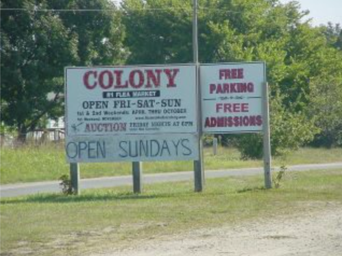 Sign for Colony Flea Market, open Friday to Sunday, with free parking and admissions, and auction details.