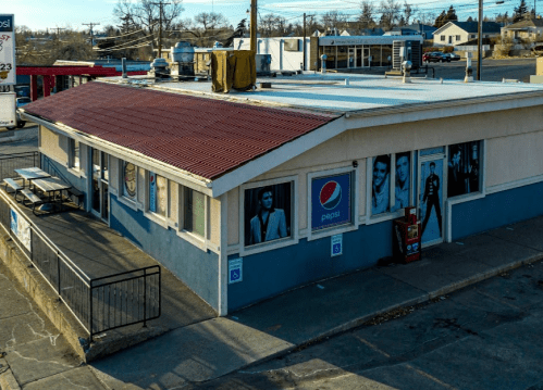 A small building with a red roof, featuring Pepsi advertisements on the walls and outdoor seating.