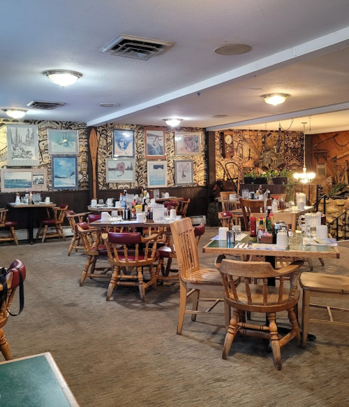 Cozy restaurant interior with wooden tables and chairs, decorated walls, and a warm, inviting atmosphere.