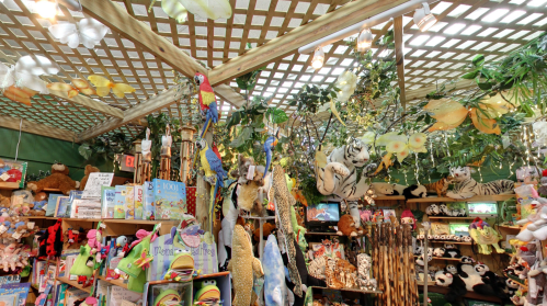 A vibrant store display filled with plush animals, toys, and colorful decorations hanging from a lattice ceiling.