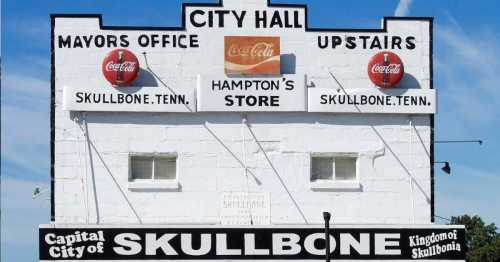 Sign for City Hall in Skullbone, Tennessee, featuring offices and a store, with Coca-Cola branding.