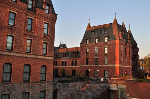 Historic brick buildings with pointed roofs and large windows, bathed in warm sunset light.