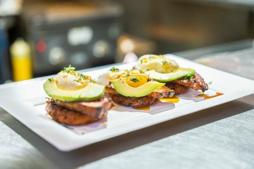 Three savory dishes featuring avocado, eggs, and a crispy base, garnished with herbs on a white plate.