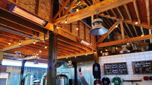 Interior of a rustic brewery with wooden beams, hanging lights, and a chalkboard menu on the wall.