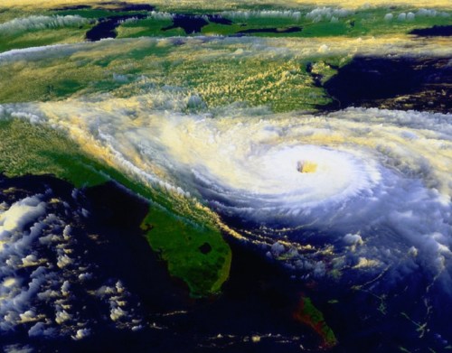 Satellite image of a powerful hurricane approaching the southeastern United States, with swirling clouds and land visible.