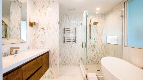 Modern bathroom featuring a glass shower, freestanding tub, and stylish wave-patterned wall. Bright and spacious design.