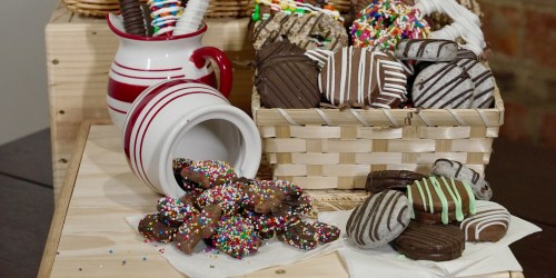 A variety of decorated cookies in a basket, with some spilled onto a table, alongside a red-striped pitcher.