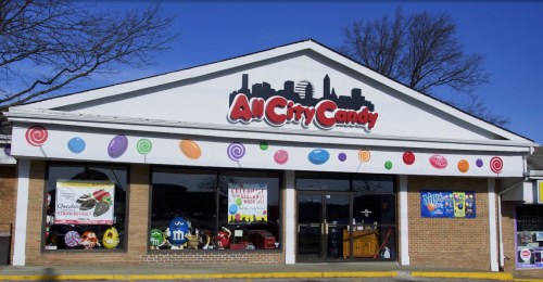 Storefront of All City Candy, featuring colorful candy-themed decorations and large windows displaying various treats.