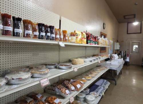 A bakery display with various pastries, cakes, and snacks on shelves in a well-lit shop.