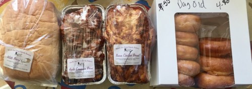 Three loaves of bread and a box of donuts, all wrapped and labeled with prices.