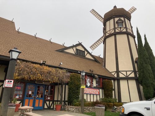A charming building with a windmill, featuring a sign that reads "Welcome to Undersen's" and lush greenery around it.