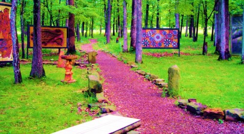 A vibrant forest path lined with colorful art displays and greenery, inviting exploration through nature.