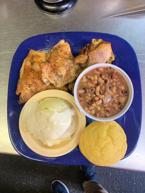 A plate of fried chicken, mashed potatoes with gravy, black-eyed peas, and a cornbread muffin.