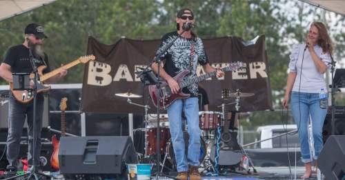 A band performs on stage with a guitarist, bassist, and a female vocalist, set against a backdrop with "Barewater" logo.