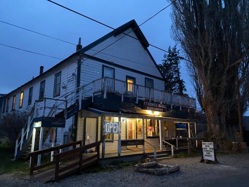 A historic building at dusk, featuring a porch, lit windows, and a sign for the Fort Howard Hotel and Brewery.