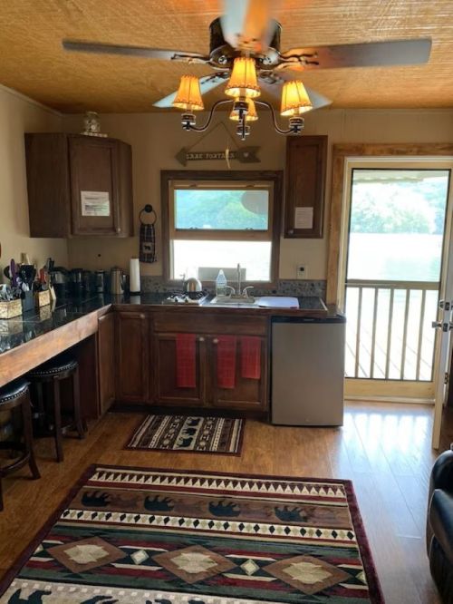 Cozy kitchen with wooden cabinets, a sink, and a door leading to a deck, featuring a patterned rug on the floor.