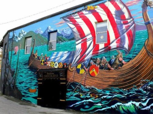 A vibrant mural of a Viking ship with red and white sails, set against a scenic ocean backdrop.