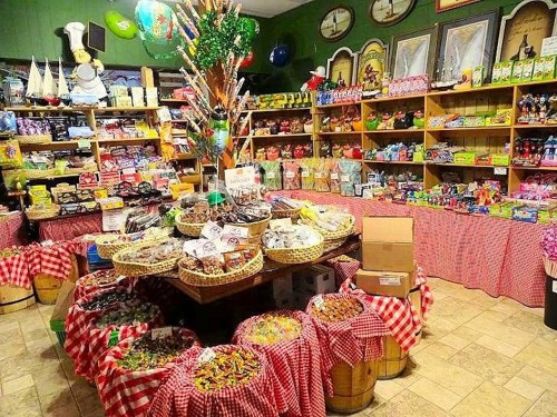 A colorful candy shop filled with various sweets, snacks, and treats displayed on tables and shelves.