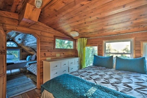 Cozy wooden bedroom with two beds, large windows, and natural light, featuring a warm, rustic design.