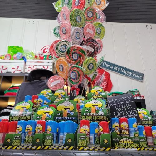Colorful display of candy, including Toxic Waste slime lickers and lollipops, in a cheerful shop setting.