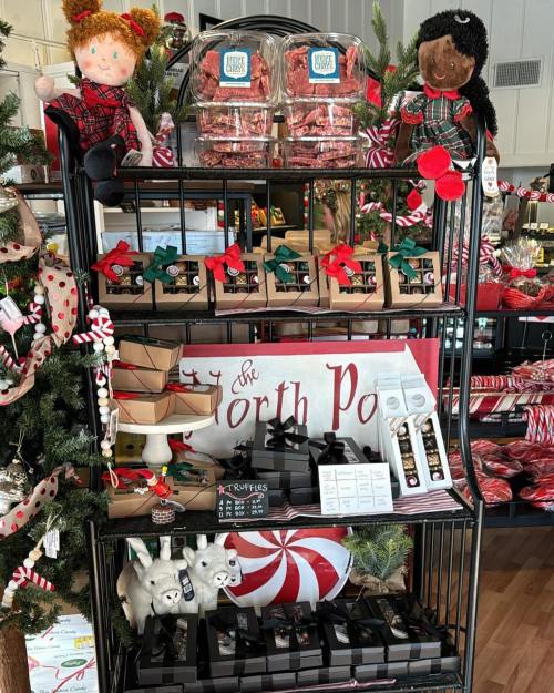 A festive display featuring dolls, candy, and assorted treats on shelves decorated for the holidays.