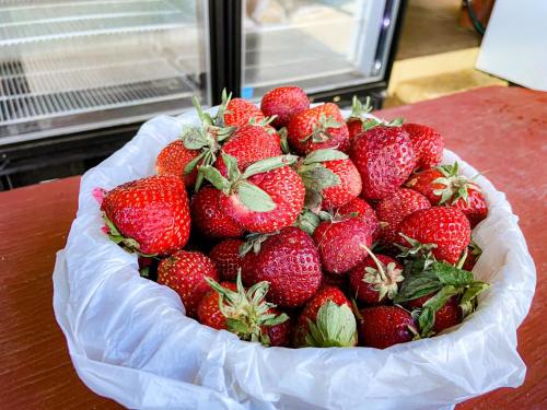 A white bag filled with fresh, ripe strawberries on a wooden surface.