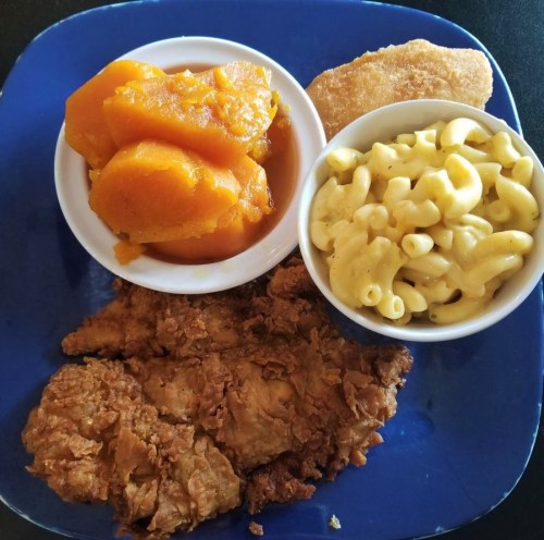 A blue plate with fried chicken, macaroni and cheese, sweet potatoes, and a cornbread muffin.