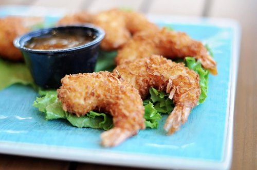 Crispy fried shrimp on a bed of lettuce, served with a small cup of dipping sauce.