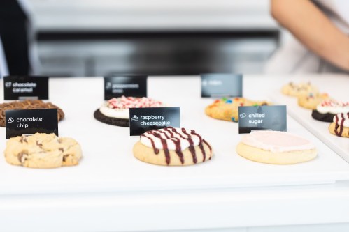 A display of various cookies with labels, including chocolate chip, raspberry cheesecake, and chilled sugar.