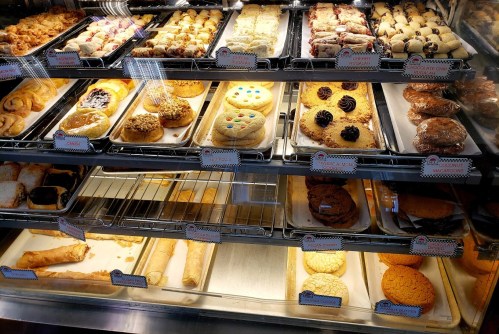 A display case filled with various baked goods, including cookies, pastries, and cakes.