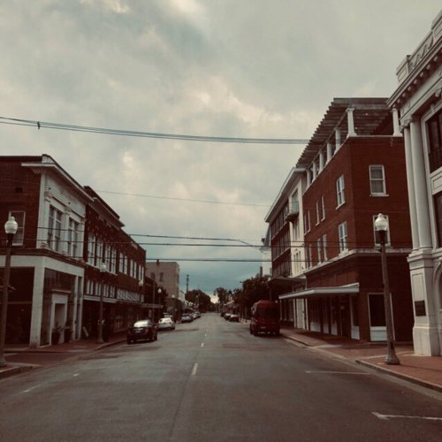 A quiet street scene with historic buildings on either side under a cloudy sky.