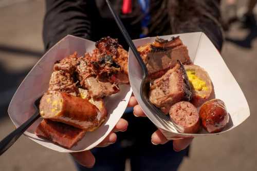 Two trays of barbecue featuring various meats, including sausage and brisket, held by a person.