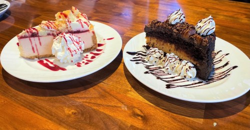 Two dessert plates: one with cheesecake drizzled in raspberry sauce, the other with chocolate cake topped with whipped cream.