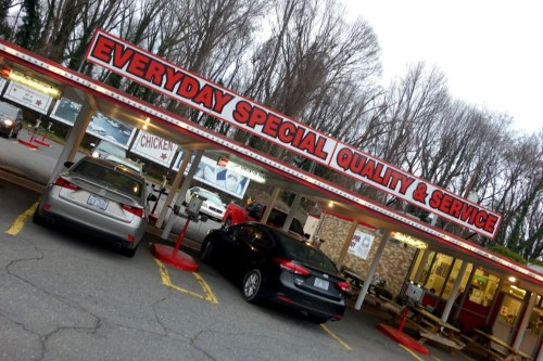 A fast-food restaurant with a red and white sign reading "Everyday Special Quality & Service" and parked cars outside.
