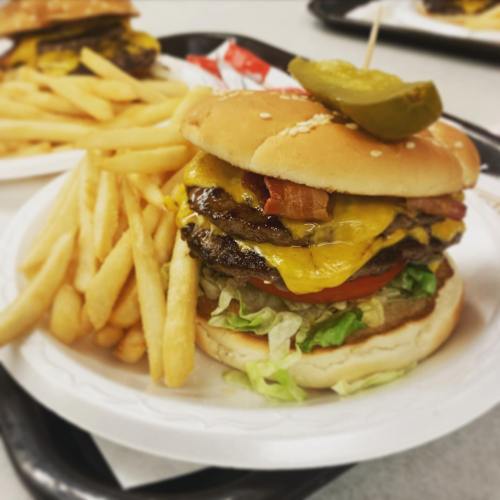 A juicy cheeseburger with bacon, lettuce, tomato, and a pickle, served with a side of golden French fries.