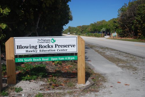 Sign for Blowing Rocks Preserve and Hawley Education Center, with a road and greenery in the background. Open 9am-4:30pm.