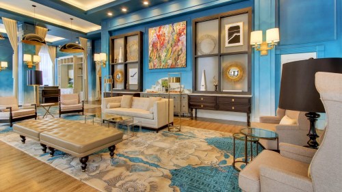 Modern lounge with blue walls, stylish furniture, artwork, and decorative accents, creating a welcoming atmosphere.