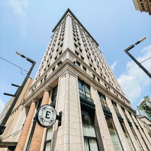 A tall, historic building with a decorative facade and a circular sign featuring the letter "E" at the entrance.
