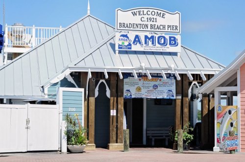 Welcome sign at Bradenton Beach Pier, featuring a wooden structure and colorful banners.