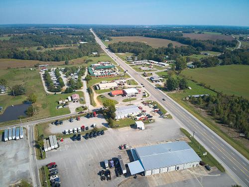 Aerial view of a rural area with a highway, businesses, and fields, showcasing a mix of commercial and natural landscapes.